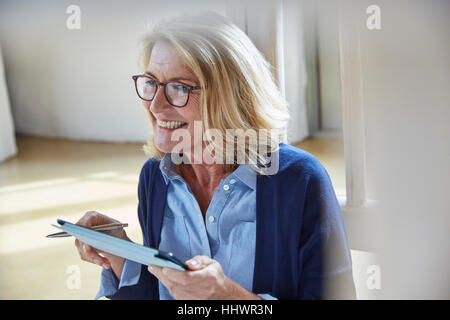 Sorridente donna senior con tavoletta digitale Foto Stock