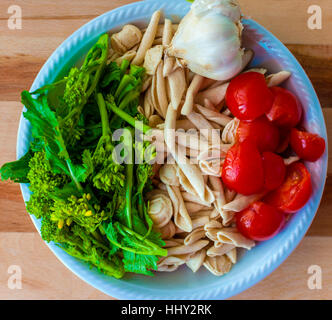 Un piatto gli ingredienti per i piatti tipici Bari: orecchiette con cime di rape. Orecchiette, pomodori, aglio e cime di rapa Foto Stock