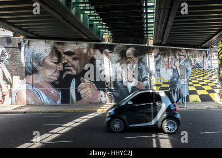Una unità di auto sotto il ponte della ferrovia dove muri dipinti raffigurano tre coppie ballare il Tango nella città di Buenos Aires, Argentina. Foto Stock