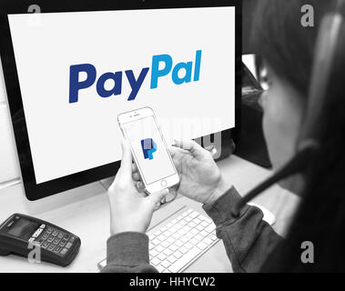 Membro del personale utilizzando il sito Web di PayPal e lo smartphone app per fornire i clienti con supporto Foto Stock