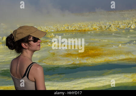 La donna nel cappello e occhiali da sole a Dalol, Danakil depressione, Etiopia e i vividi colori di giallo e verde delle strane forme di cristallo Foto Stock