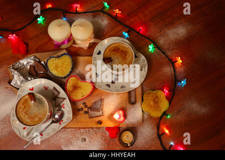 Due belle tazze di cappuccino con candele e cioccolato per gli amanti in atmosfera romantica Foto Stock