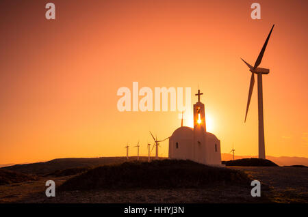 Le turbine eoliche in una fattoria eolica con una piccola chiesa al tramonto, Creta, Grecia Foto Stock