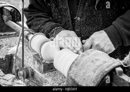 Un artigiano si ritaglia un pezzo di legno utilizzando un vecchio manuale tornio. Foto Stock