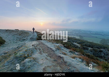 Un viandante sfidando le temperature di congelamento come egli prende un inizio di mattina a piedi su Moel y Gaer hill fort vicino al villaggio di Rhosesmor, Flintshire, Galles Foto Stock