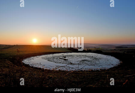 Brighton, Regno Unito. Xxi gen, 2017. Il sole sorge su un laghetto di rugiada sul South Downs Way a Ditchling Beacon appena a nord di Brighton questa mattina con temperature meteo per essere ben al di sotto del punto di congelamento nel sud della Bretagna Credito: Simon Dack/Alamy Live News Foto Stock