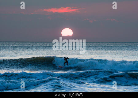 Aberystwyth Wales UK, sabato 21 gennaio 2017 UK meteo: dopo un freddo la notte, con temperature ben al di sotto dello zero, surfisti godersi le onde al tramonto alla fine di una bella giornata di sole caldo in Aberystwyth su Cardigan Bay costa del Galles occidentale foto Keith Morris / Alamy Live News Foto Stock