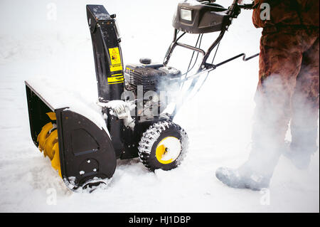 L'uomo inizia il motore del ventilatore di neve Foto Stock