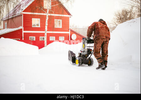 Uomo di funzionamento del ventilatore di neve per rimuovere la neve sul viale di accesso Foto Stock