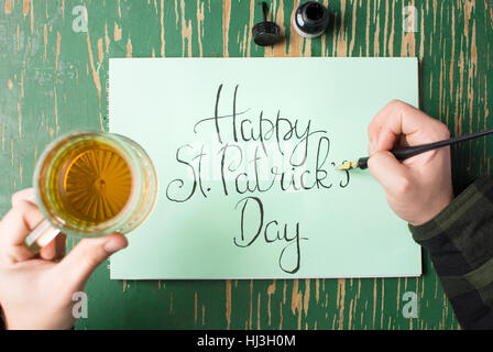 L'uomo con una birra con felice St Patrick giorno scheda di calligrafia Foto Stock