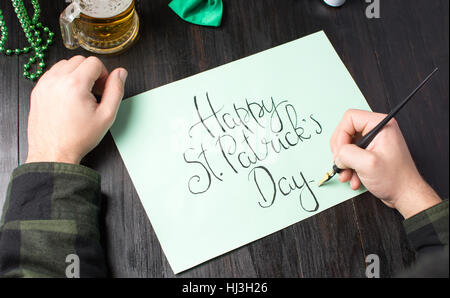 Mani maschio iscritto una felice St Patrick giorno scheda di calligrafia Foto Stock