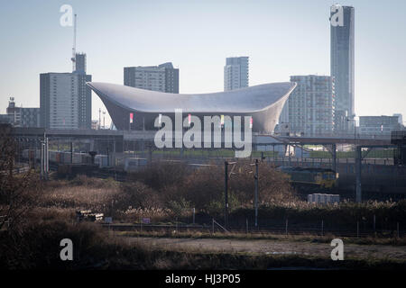 Un treno merci passa il London Aquatics Centre presso la Queen Elizabeth Parco Olimpico di Stratford, a est di Londra. La Londra di sviluppo Legacy Corporation ha stabilito un ambizioso piano per rigenerare la zona attorno al sito del 2012 Giochi Olimpici, creando un mix di alloggiamento, spazio business e servizi pubblici. Foto Stock