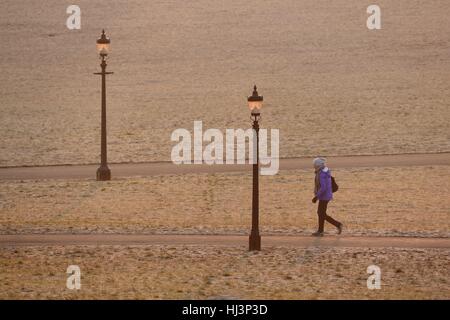 Un inizio di mattina di walker è illuminato da un freddo gelido sunrise in Primrose Hill a Londra. Foto Stock