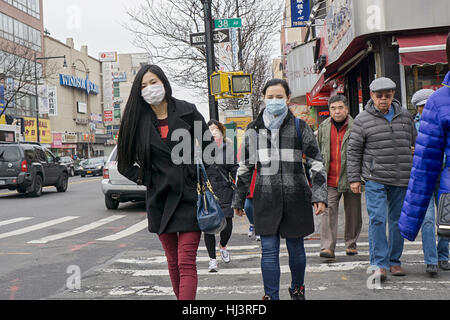Cinese di due giovani donne che indossano maschere chirurgiche attraversare una strada trafficata su Main Street a Chinatown, il centro cittadino di lavaggio, Queens, NYC Foto Stock