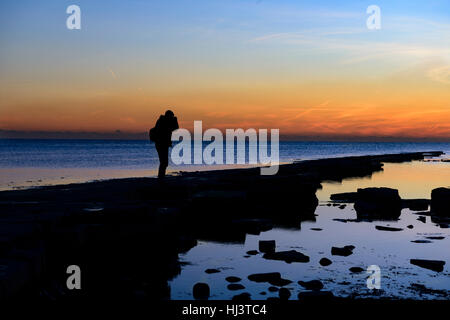 L'uomo stagliano al tramonto sul litorale Foto Stock