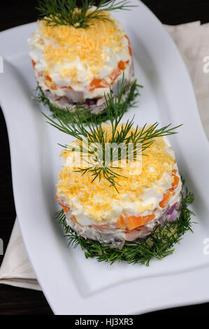 Insalata tritate impilati aringa con patate, carote, cipolle, Uova con maionese disseminata con scorza di tuorlo d'uovo Foto Stock