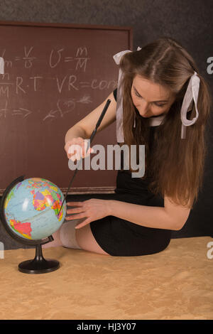 Affascinante ragazza mostra il paese sul globo. Foto Stock