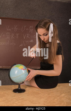 Affascinante ragazza mostra il paese sul globo. Foto Stock