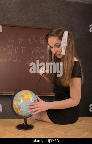 Affascinante ragazza mostra il paese sul globo. Foto Stock