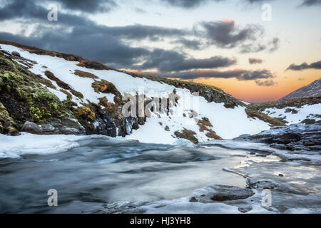 Un freddo fiume nevoso nelle Highlands di Islanda incorniciata dai cieli pastello e scoscesi offre paesaggio panoramico epitomizing congelata di deserto. Foto Stock