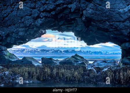 Un landmark beach in Islanda chiamato Dinosaur Rock ha un foro che offre una vista spettacolare della costa islandese. Foto Stock