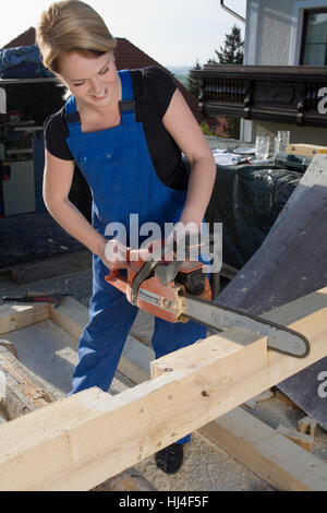 Giovane donna lavora con una sega a catena Foto Stock