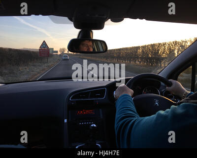 La guida su A303 al mattino presto in inverno. Autista riflesso nel retrovisore. Foto Stock