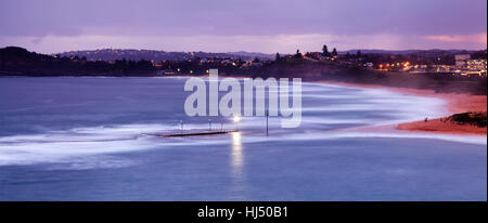 Sydney Nord spiagge mona vale rock pool scollegato dalla sabbia di alta marea al tramonto con la strada illuminata la luce in un'acqua. Foto Stock