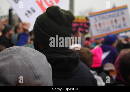 Distretto di Columbia, Stati Uniti d'America. 21 gen, 2017. Un uomo guarda su manifestanti marciano lungo la Constitution Avenue NW, il Monumento di Washington visto in lontananza. Foto Stock