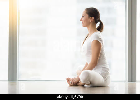 Giovane donna attraente in baddha konasana pongono contro il piano win Foto Stock