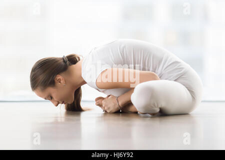 Giovane donna attraente in baddha konasana pongono contro il piano win Foto Stock