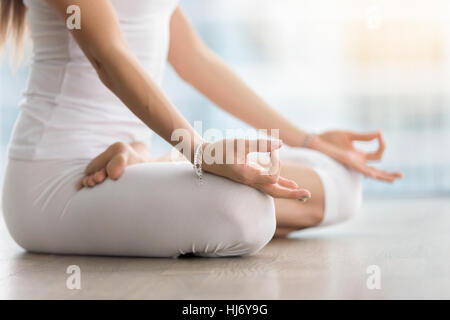 Donna in Padmasana posano con mudra contro la piano window, primo piano Foto Stock