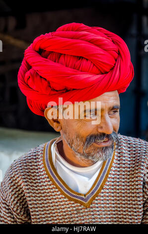 Closeup ritratto di un senior di Rajasthani cittadino nella sua fattoria indossando rosso turbante tradizionale Foto Stock