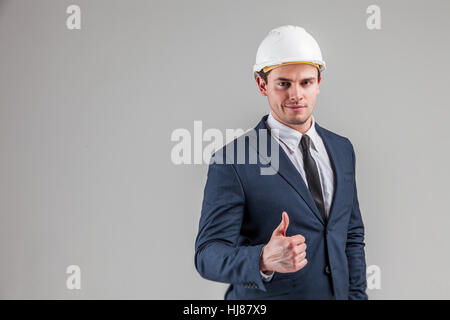 Ritratto di un imprenditore nel casco bianco su sfondo grigio Foto Stock