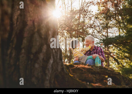 Nonna e nipote seduta nella foresta di parlare Foto Stock