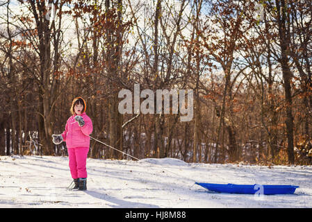 Ragazza tirando la sua slitta attraverso la neve Foto Stock