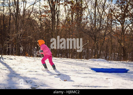 Ragazza tirando la sua slitta attraverso la neve Foto Stock