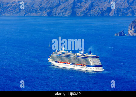 La nave di crociera la celebrità di vela di riflessione nel profondo blu azzurro mare Mediterraneo all'interno della caldera dell'isola greca di Santorini Foto Stock