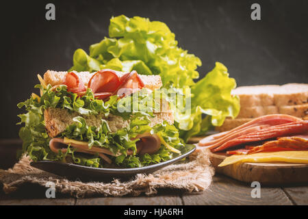 Club sandwich su un tavolo rustico con ingredienti Foto Stock