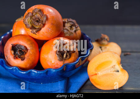 Arance mature hachiya cachi in vaso blu Foto Stock