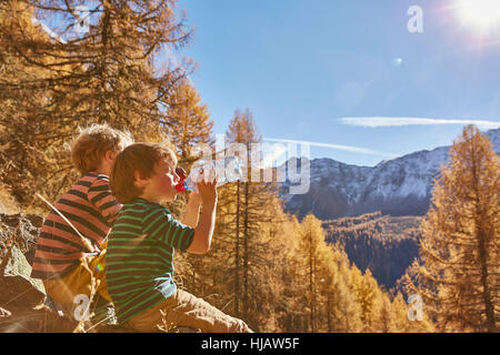 Due ragazzi seduti sulle rocce, bere acqua da bottiglie, Val Senales Alto Adige - Italia Foto Stock
