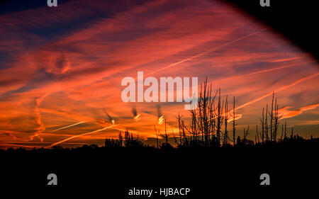 Una forma a spirale nuvole causando ombre su altre nubi in alba rossa Foto Stock