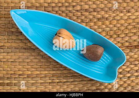 Due semi di Avocado servito in una piastra di colore blu Foto Stock