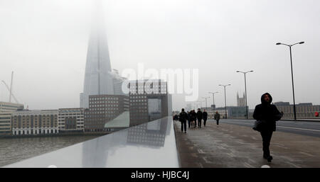 Pedoni cross London Bridge con il Coccio avvolta nella nebbia dietro di loro, come nebbia fitta causato interruzioni di viaggio attraverso il sud dell'Inghilterra, con migliaia di passeggeri aerei rivolta verso le cancellazioni e ritardi. Foto Stock