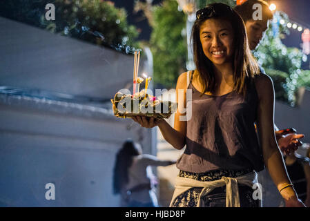 Giovane donna alla Loy Krathong festa delle lanterne, rilasciando lanterna oscillante verso il basso del fiume Ping, Chiang Mai, Thailandia Foto Stock