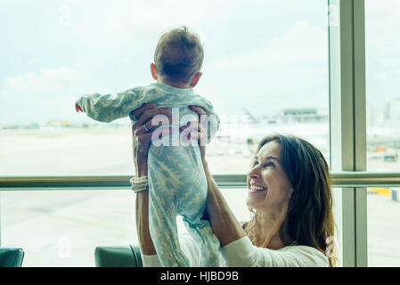 Nonna baby di sollevamento a metà in aria all'aeroporto Foto Stock