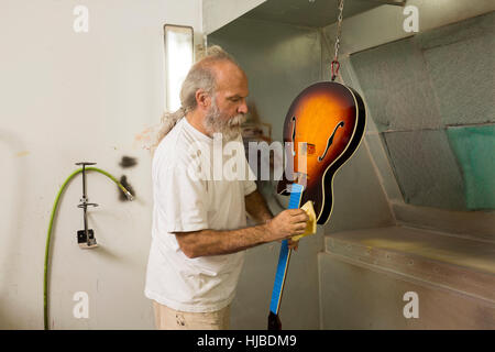 Liutaio in laboratorio usando il panno per chitarra di vernice Foto Stock