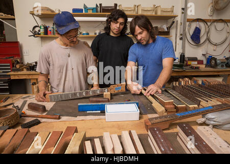 Guitar maker in laboratorio controllo qualità colli di chitarra Foto Stock