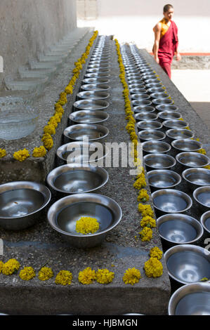 Il Tibetano monaco buddista a piedi attorno a uno stupa con acqua Vaso offerte al monastero di Sera Je, India. Foto Stock