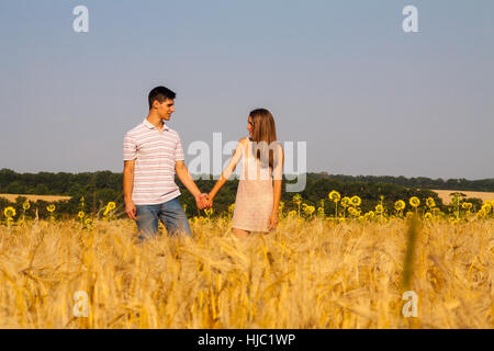 Felice coppia giovane camminare insieme attraverso il campo di grano Foto Stock